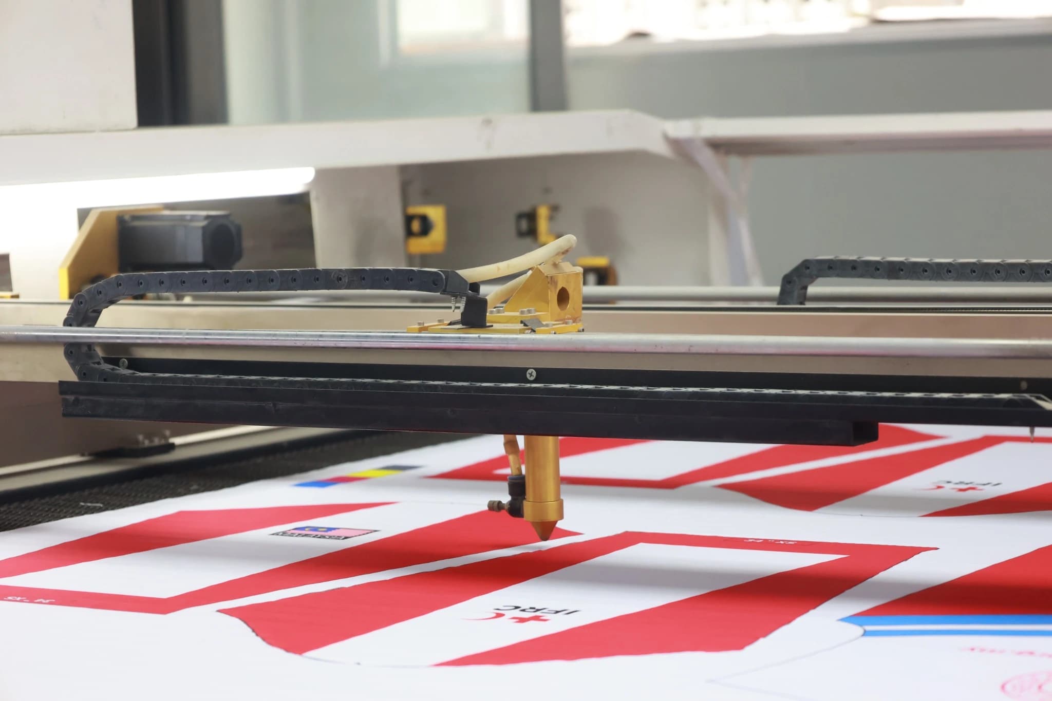 Moving cutting head and rail above a printed sportswear panel layout