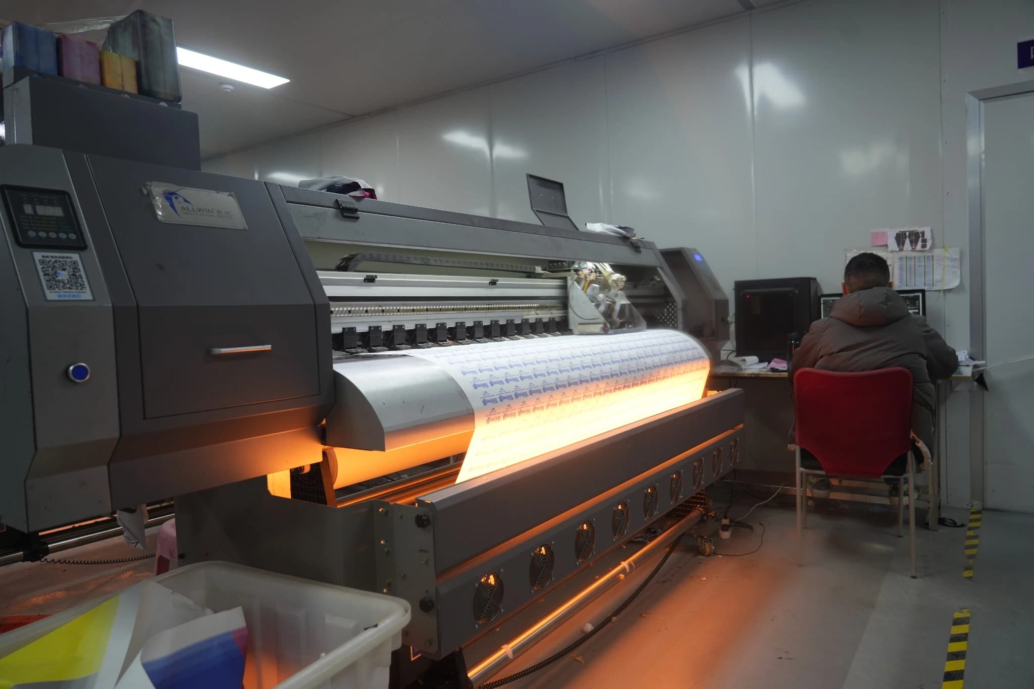 TONTON operator seated beside a roll-to-roll printer producing patterned transfer paper