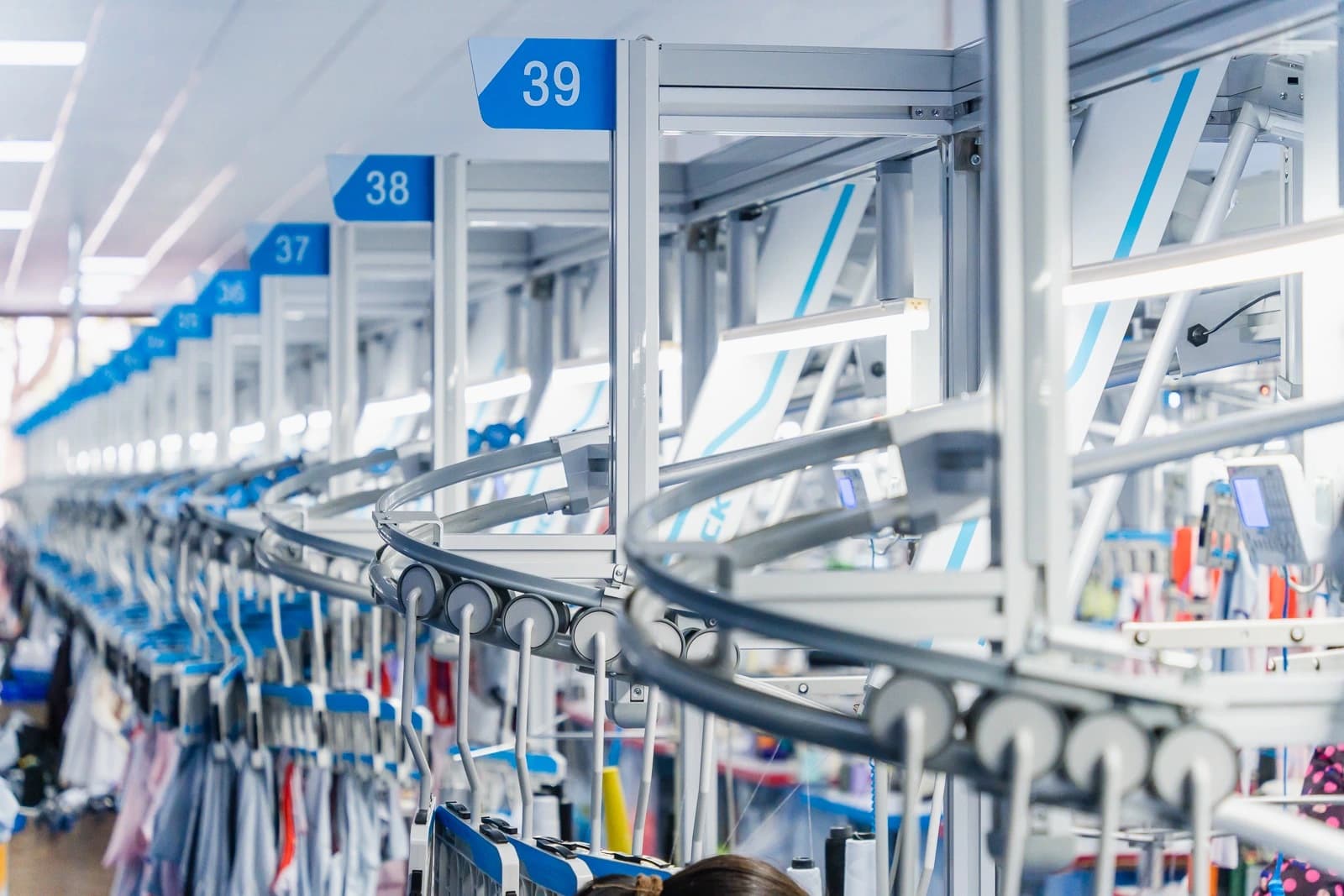 Numbered workstations and overhead garment carriers in the TONTON workshop