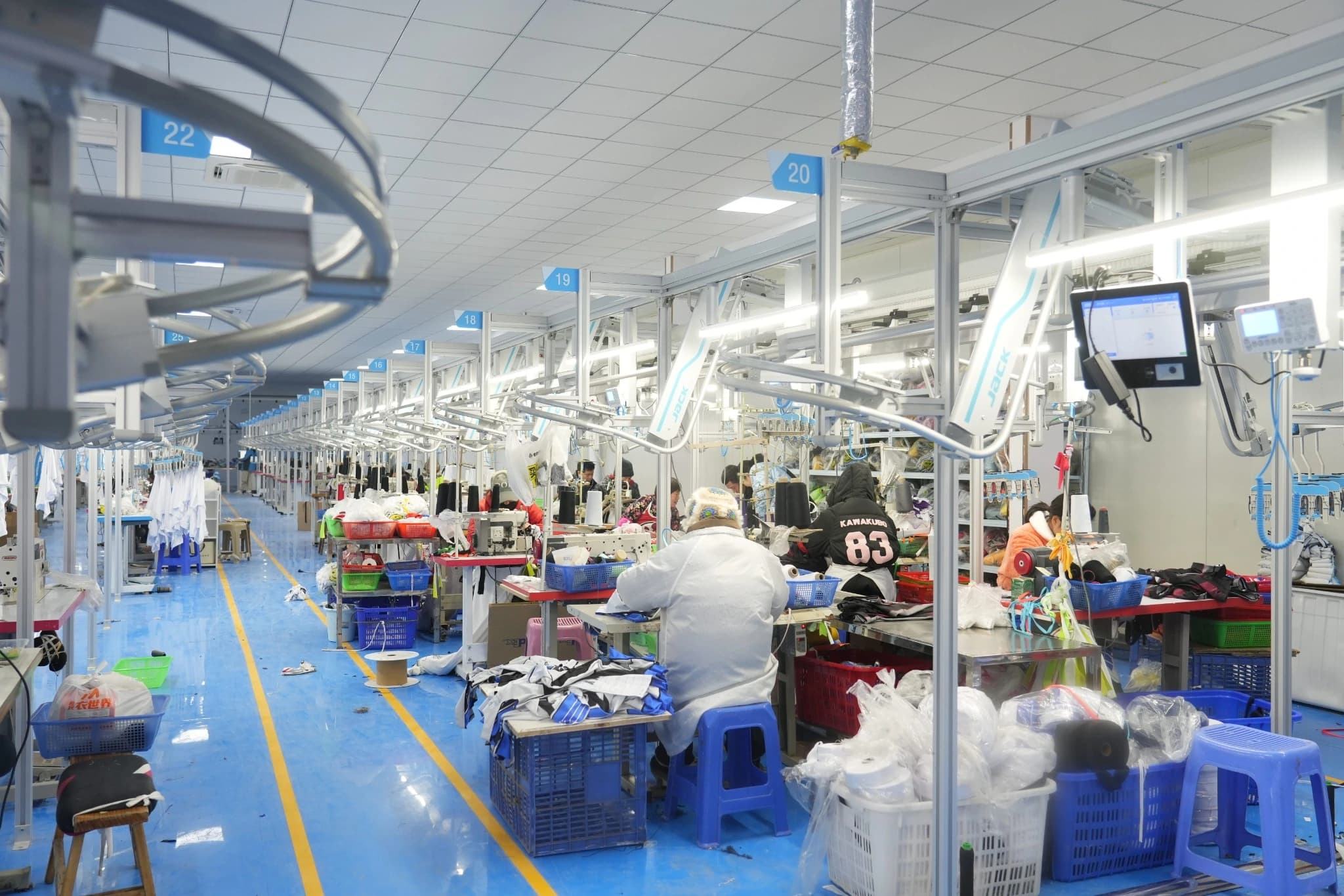 TONTON workshop aisle with overhead hanging tracks, garment carriers and sewing stations