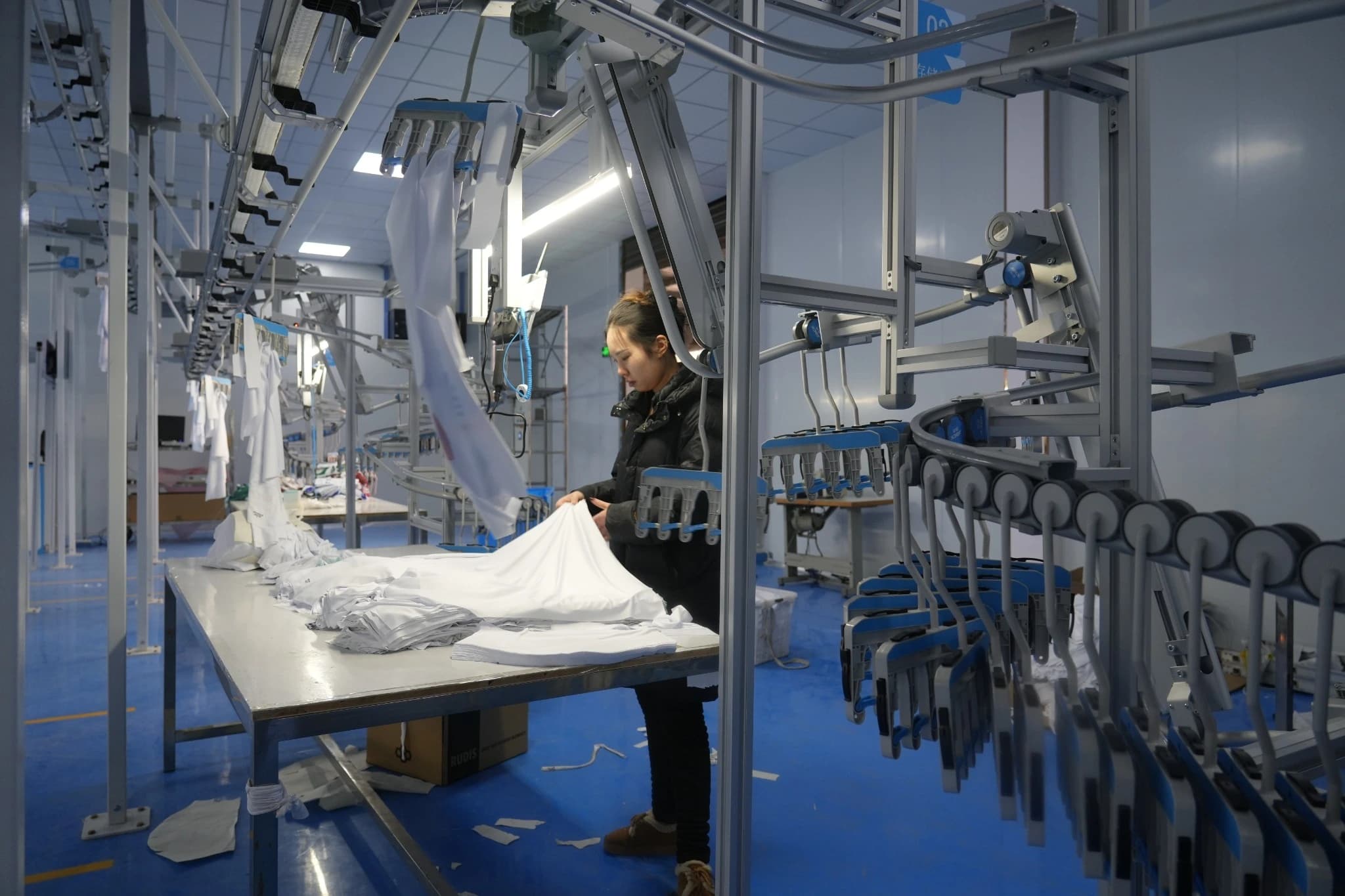 Garment panels and dedicated carriers beside a sewing workstation on the hanging line