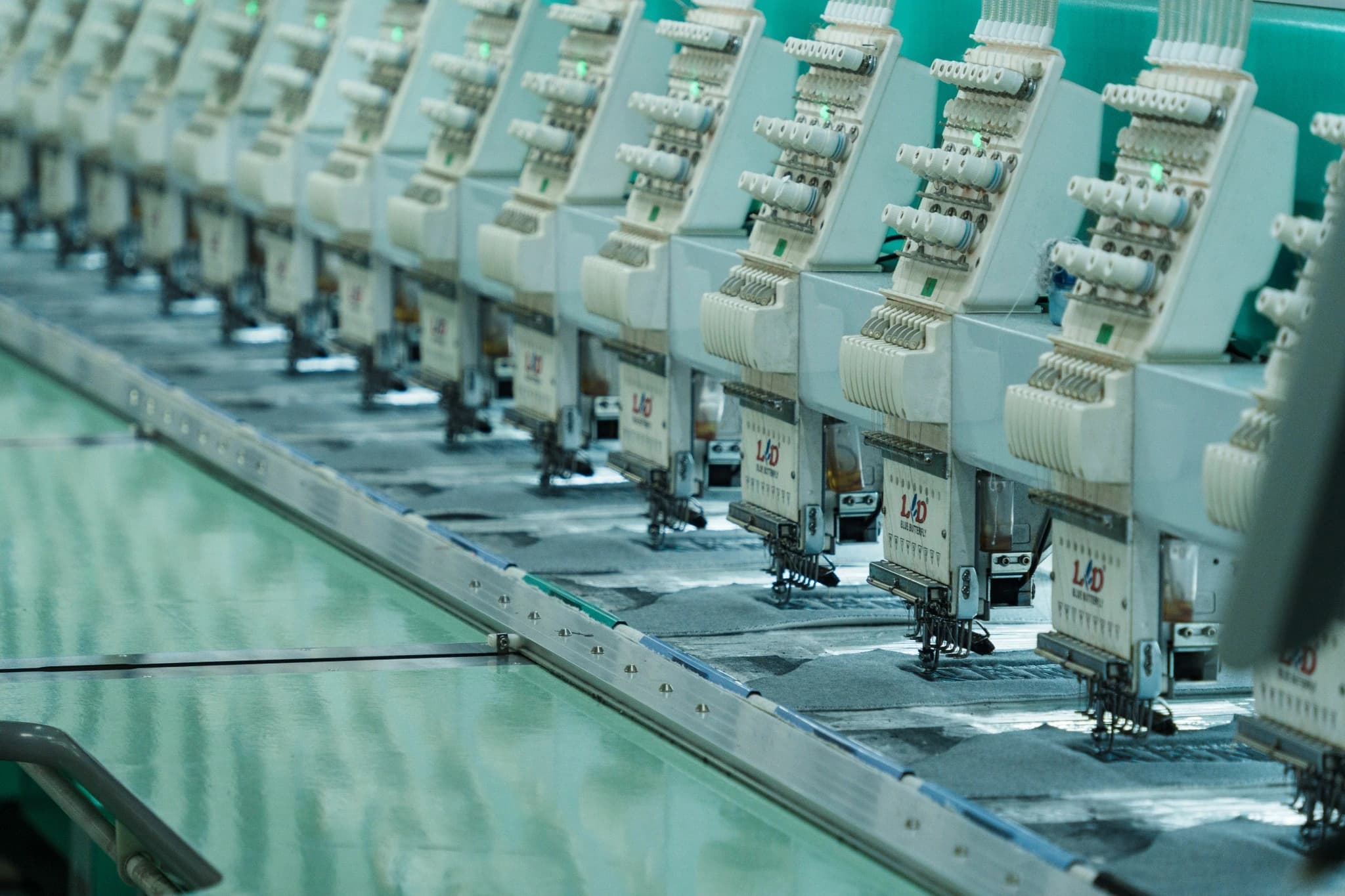 Angled view along the row of TONTON embroidery machine heads