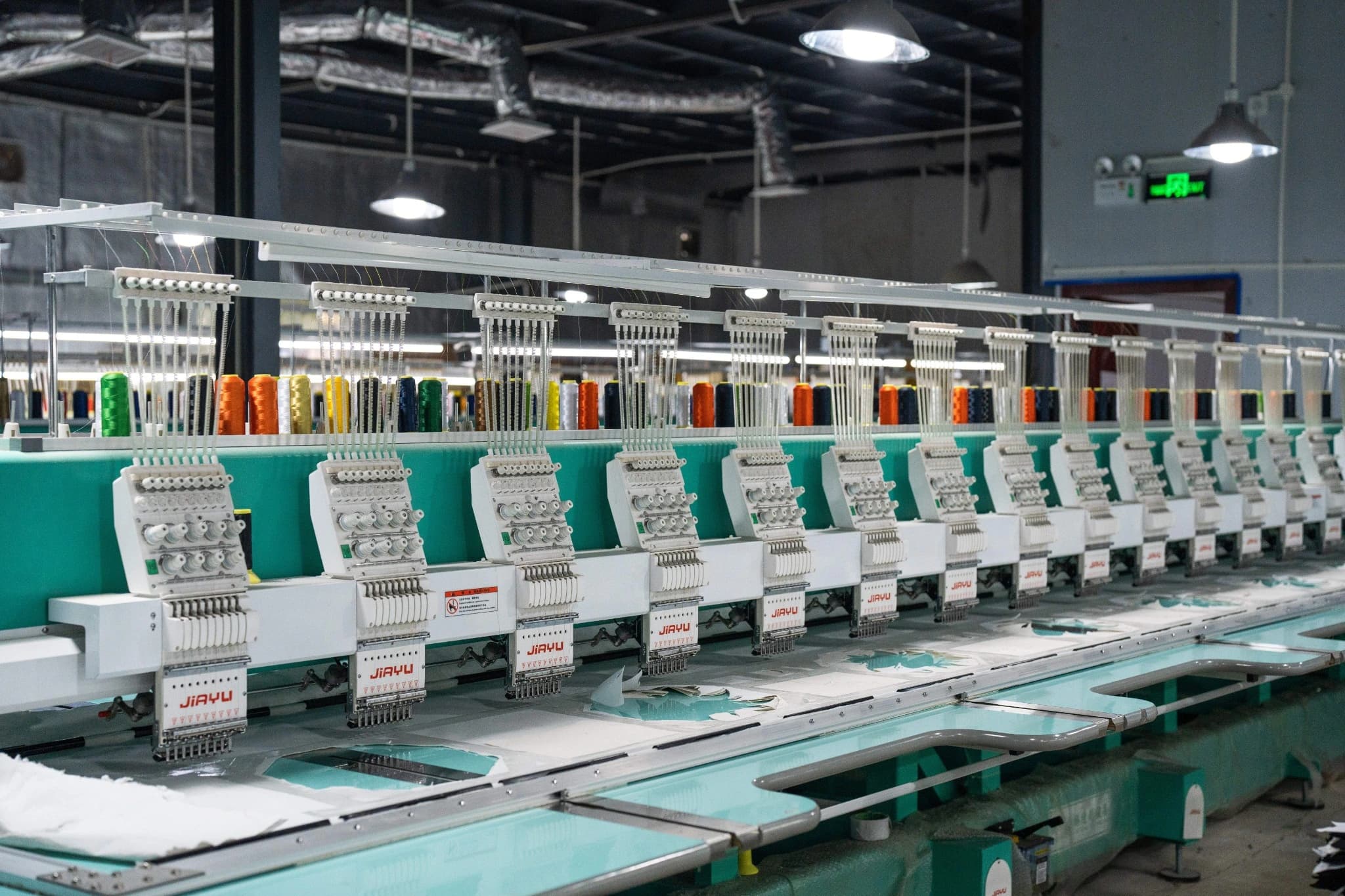 Colored thread cones above multi-head embroidery equipment at TONTON