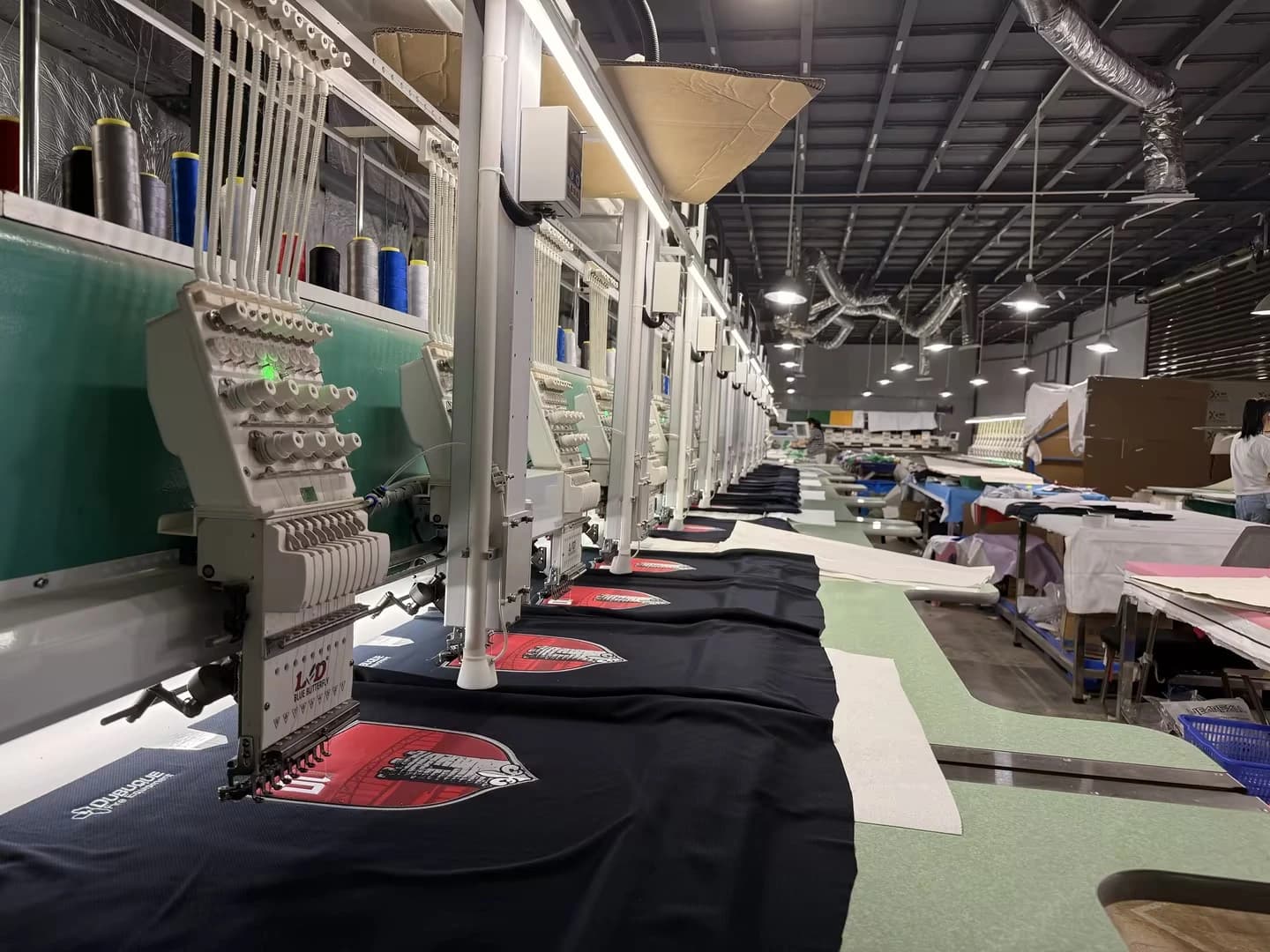 Side view of embroidery heads and dark garment panels in the workshop