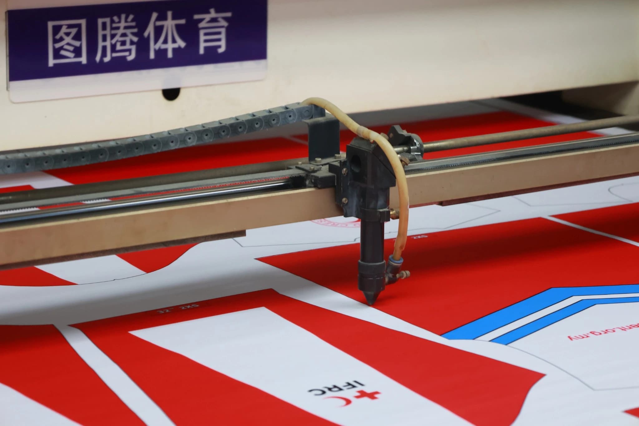 Cutting equipment positioned over printed sportswear panels