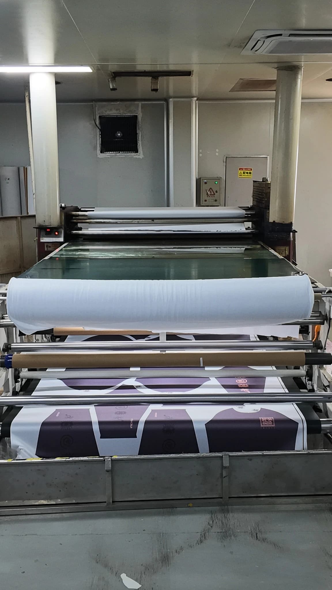 Front view of TONTON's rotary heat transfer machine with fabric and printed material at the rollers