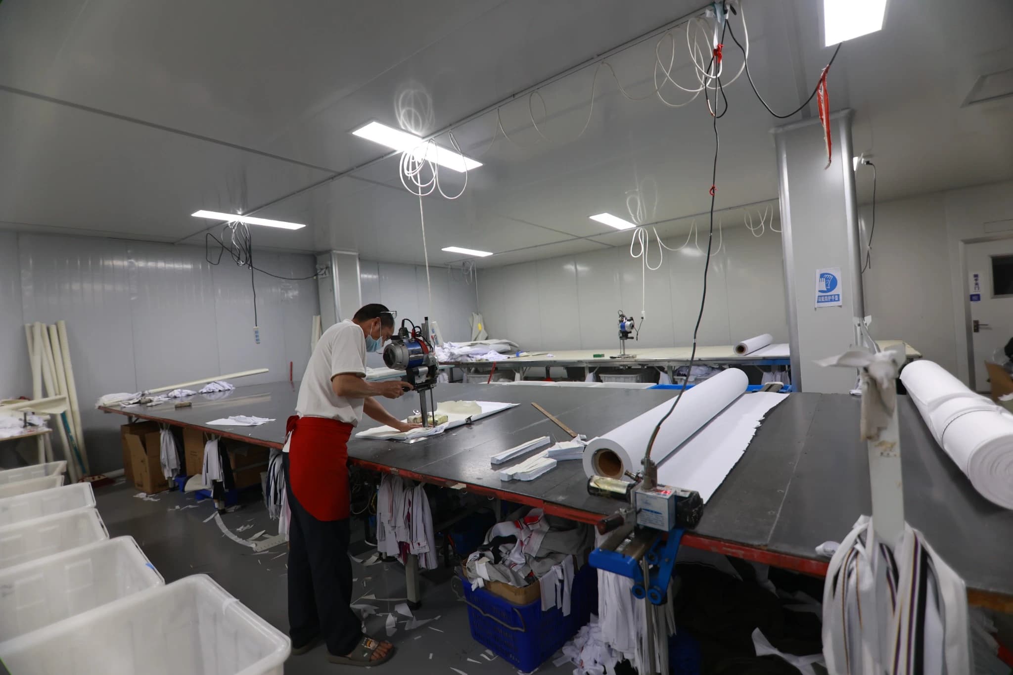 Wide view of TONTON's fabric cutting table, operator and workshop