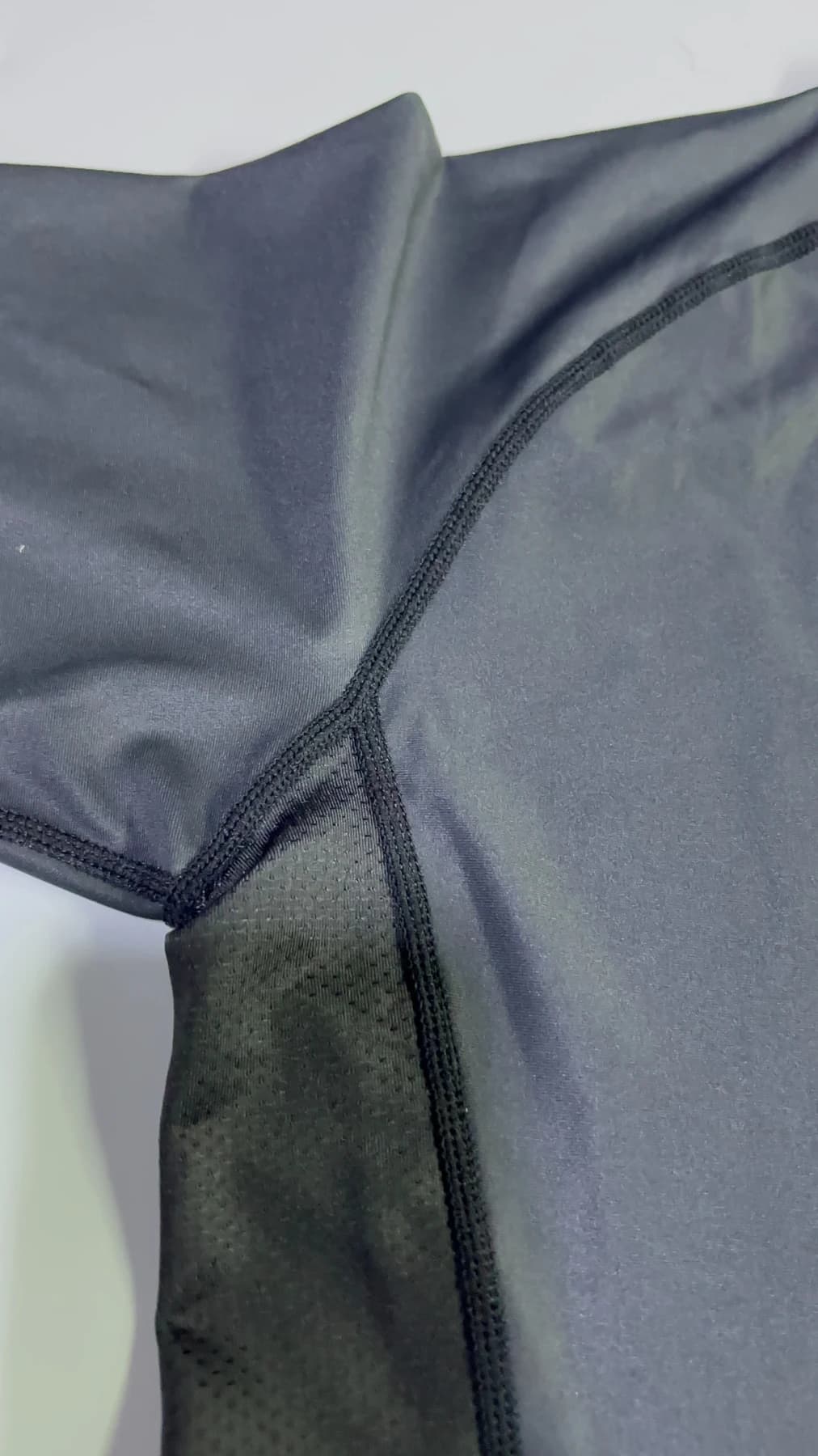 Close view of a mesh insert and panel stitching on the supplied rash guard