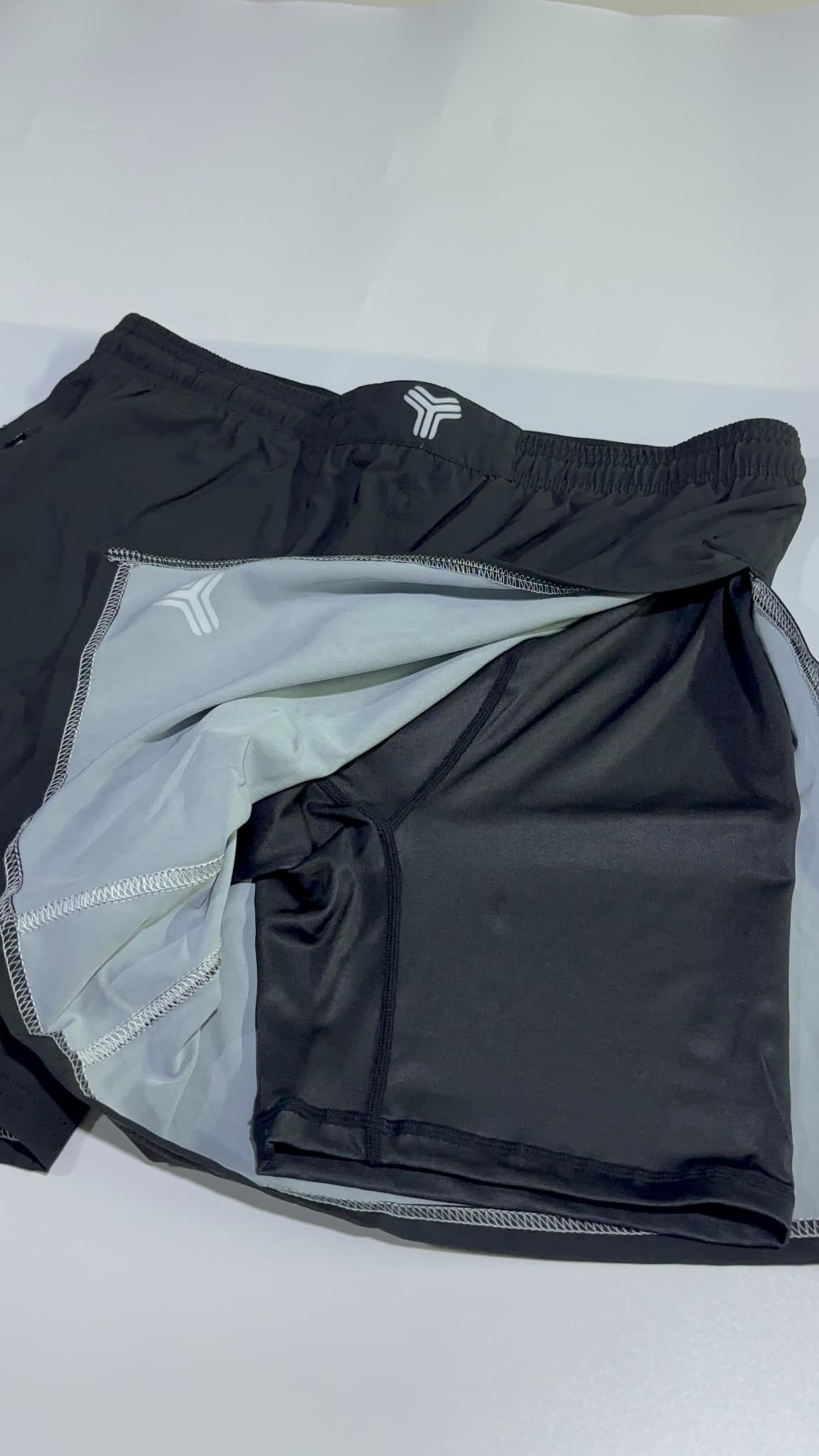 Supplied high-split shorts opened to show the dark outer shell, light inner layer and stitched panel seams