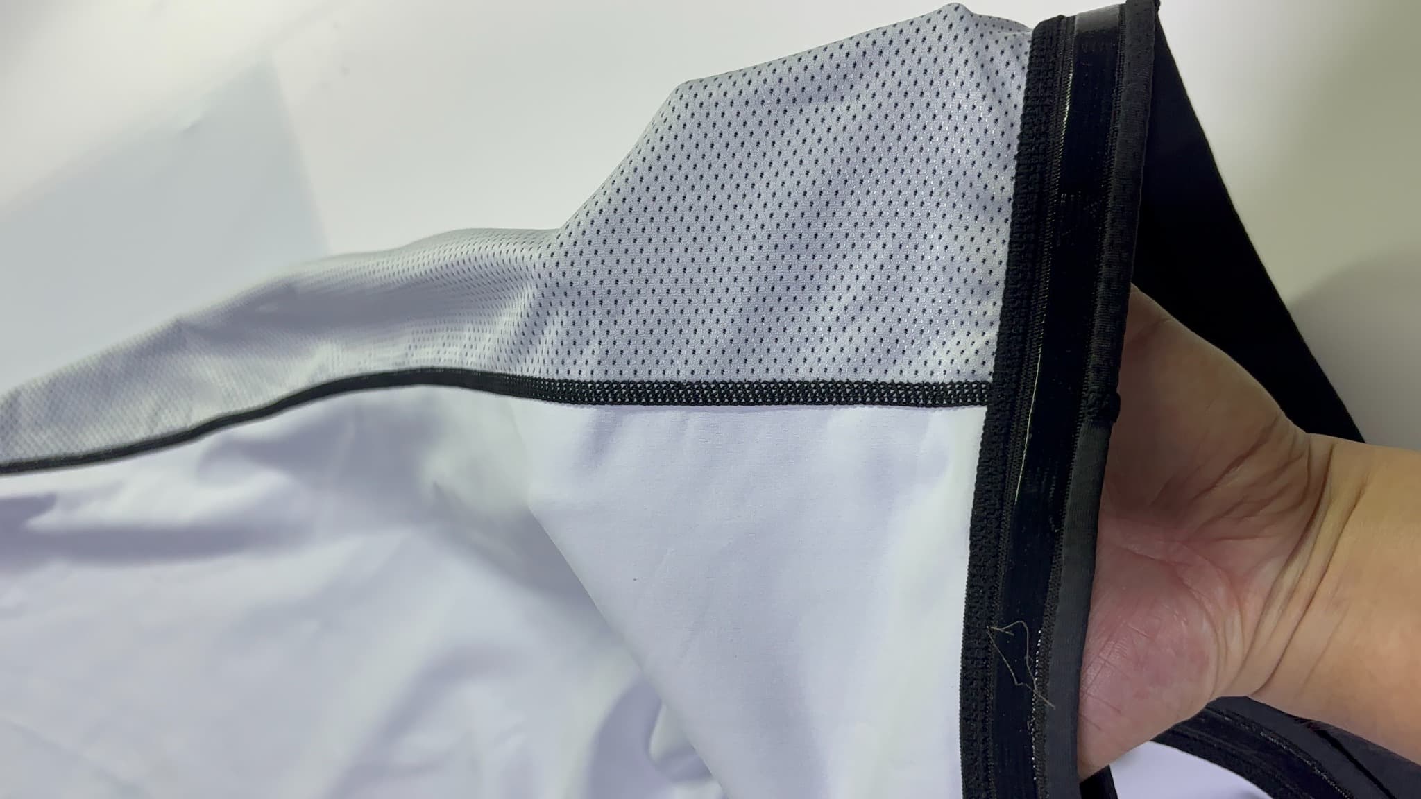 Actual supplied stretch mesh insert held open to reveal small openings and stitched panel joins