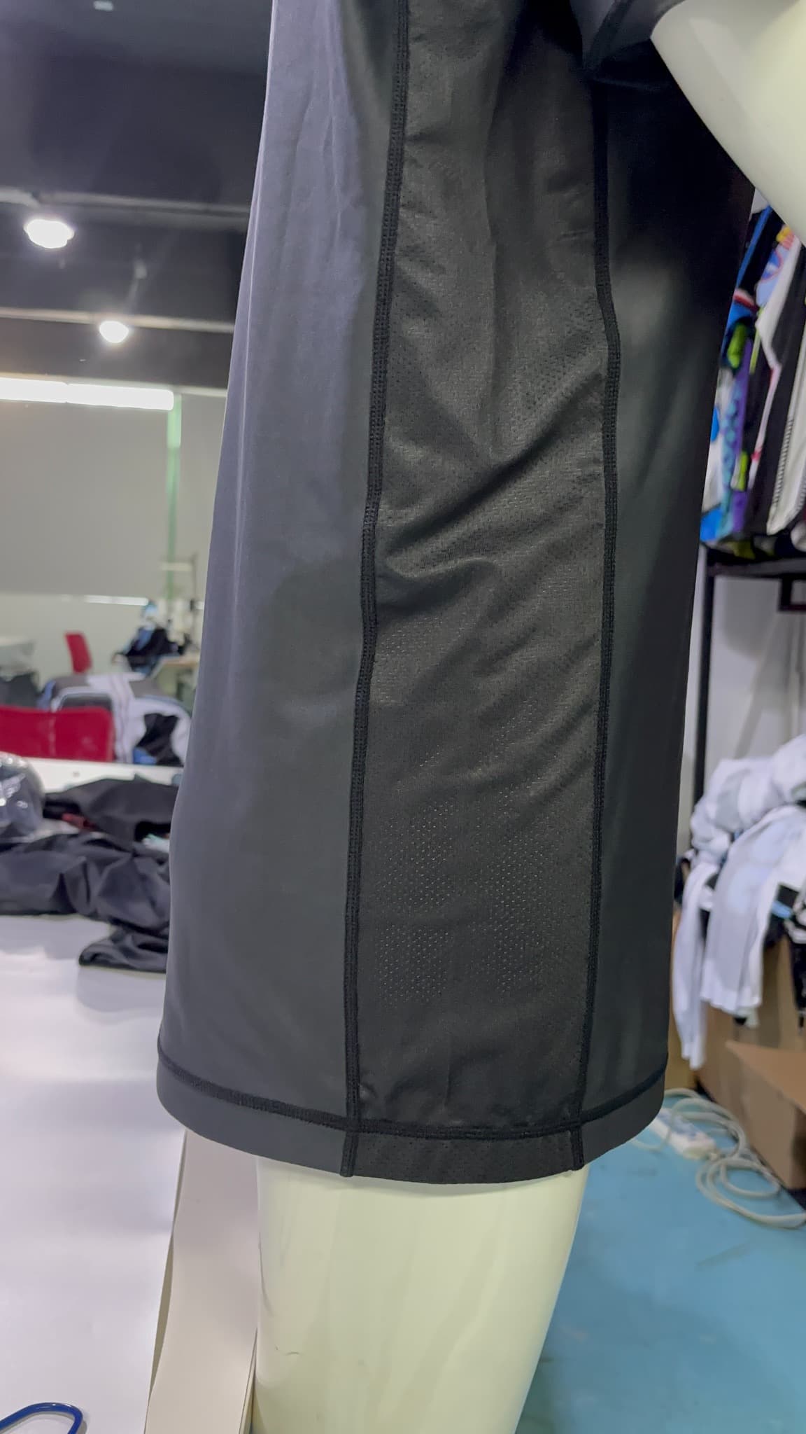 Actual supplied outer view of a dark garment with a vertical mesh insert between panel seams