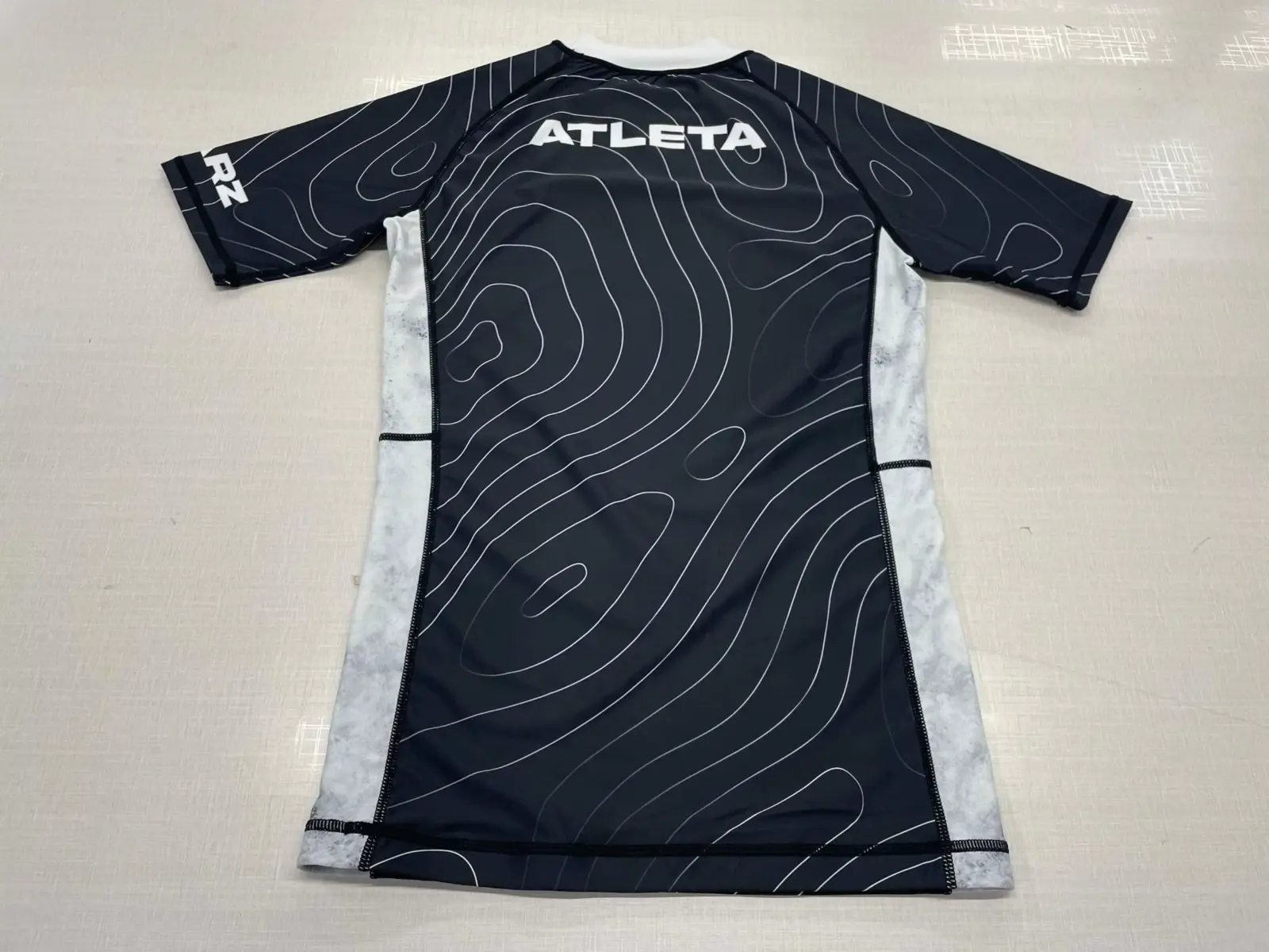 Customer-supplied back photograph of a finished black and white Athleta long-sleeve custom Rash Guard with contour-line graphics