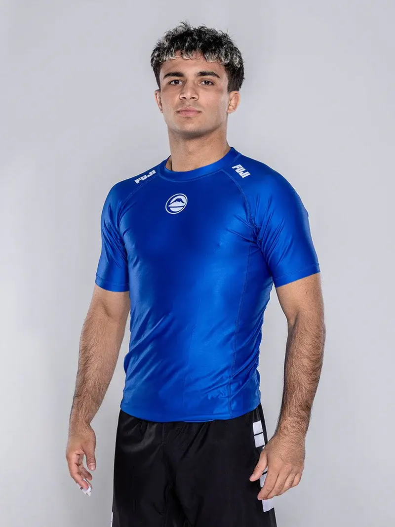 Three-quarter view showing the shoulder and side construction of the blue Elite Team Rash Guard