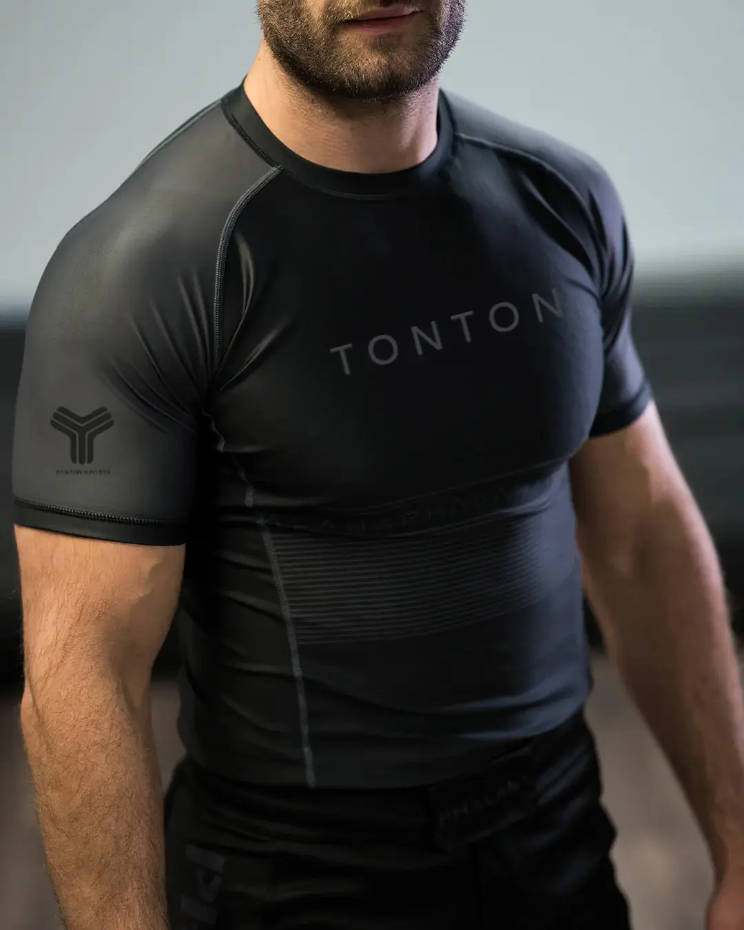 Close-up of black Rash Guard chest, raglan seam, and tonal branding