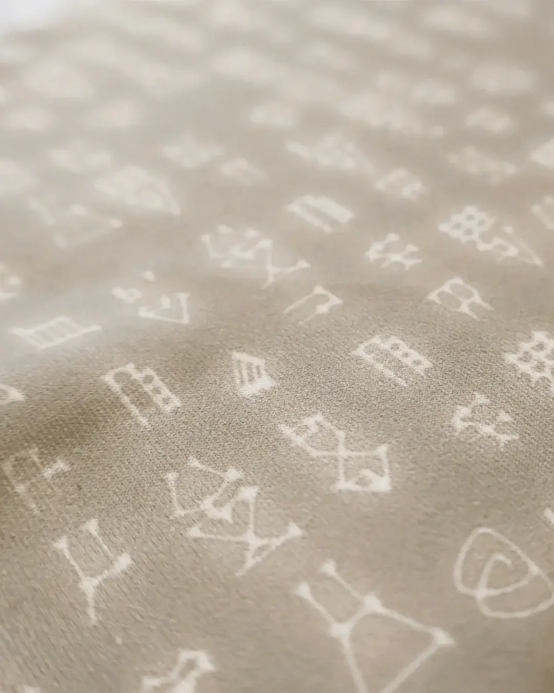 Close-up of taupe sublimated performance fabric with a repeating custom pattern